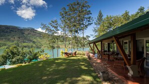 A lakeside property with a patio area, outdoor seating, and a view of the lake and surrounding hills.