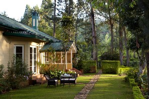 A house with a green roof, a garden with a lawn, and a pathway leading to the house.