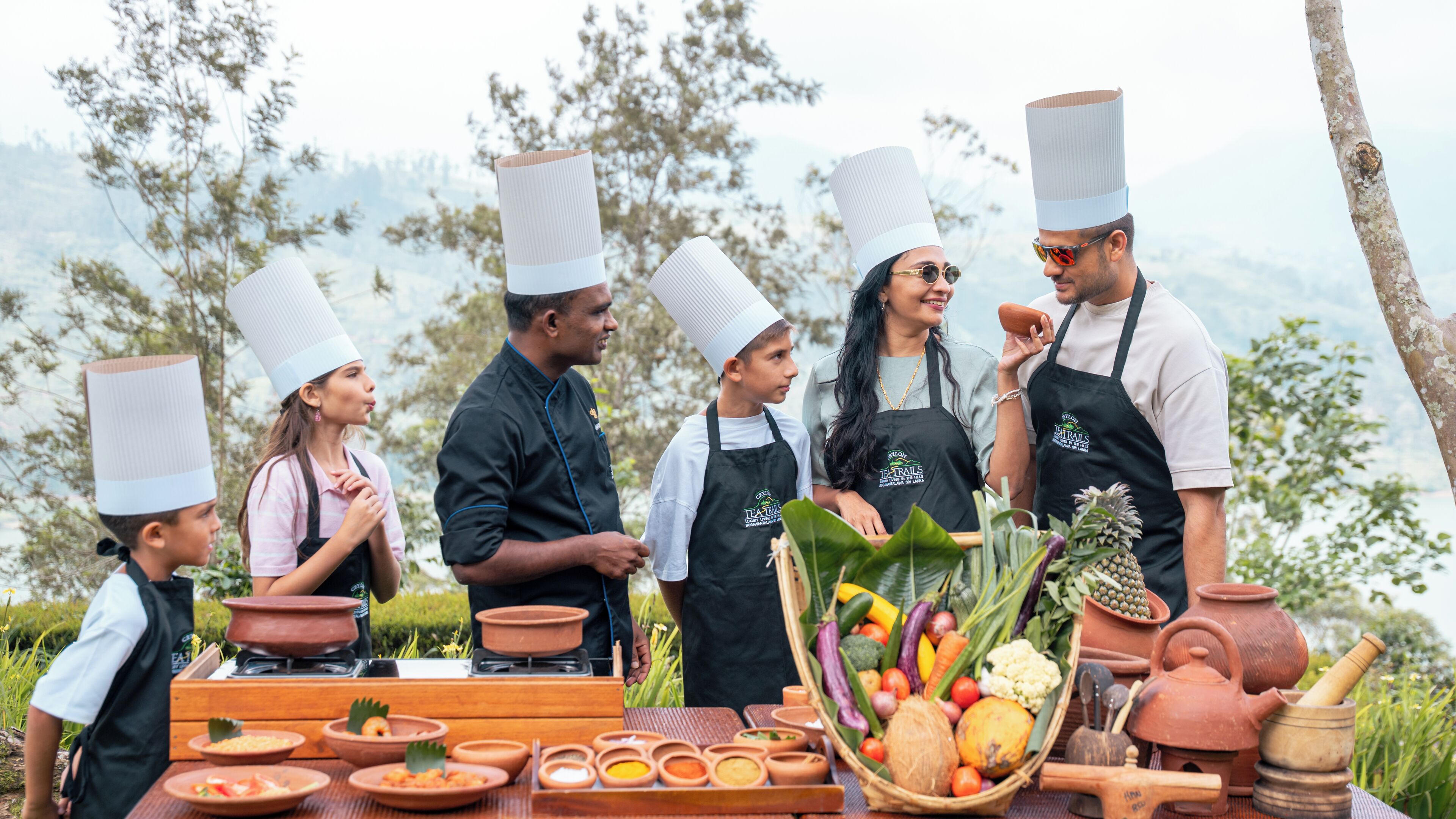 A group of people wearing chef hats and aprons, standing around a table with cooking utensils and ingredients.