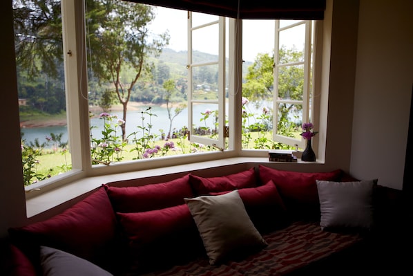 A room with a large window overlooking a lake and greenery.