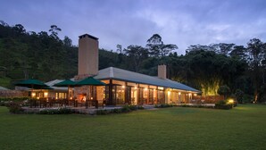 A modern building with a large patio area, outdoor seating, and a well-maintained lawn. - Ceylon Tea Trails - Relais and Chateaux - All Inclusive (Hatton)