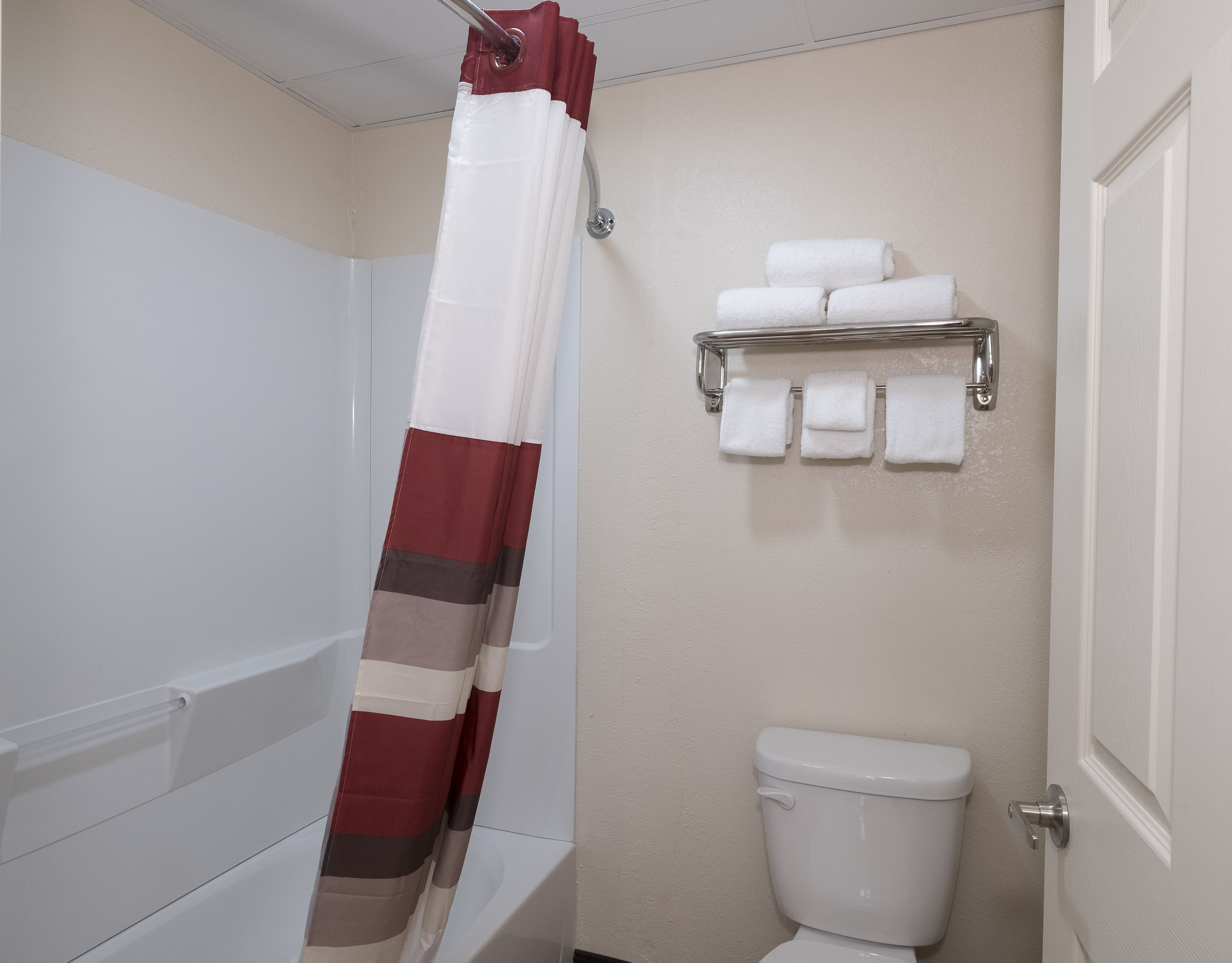 Un baño con cortina de ducha, inodoro y toallero con toallas.