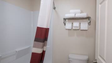 Un baño con cortina de ducha, inodoro y toallero con toallas.