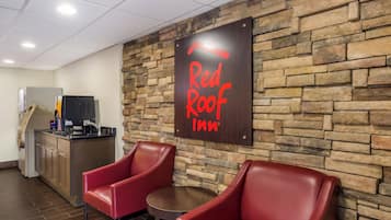 A Red Roof Inn sign, a kitchenette, and two leather chairs in a room.