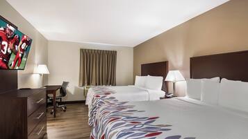 A hotel room with a bed, desk, chair, and a television on the wall.