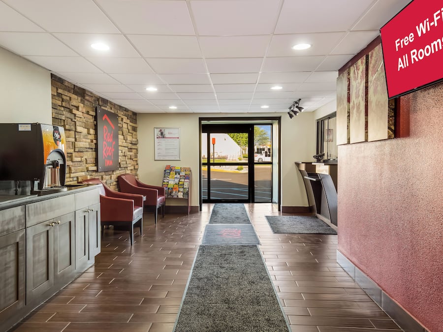 Un vestíbulo de hotel con mostrador de recepción, zona de estar y un letrero que indica acceso a Wi-Fi gratuito.