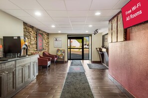 Een hotel lobby met een receptiebalie, een zithoek en een bordje dat gratis wifi aangeeft.