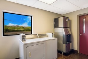 A laundry room with a washer and dryer, a water cooler, and a window with a view of a road and greenery. - Red Roof Inn Allentown South (Allentown)