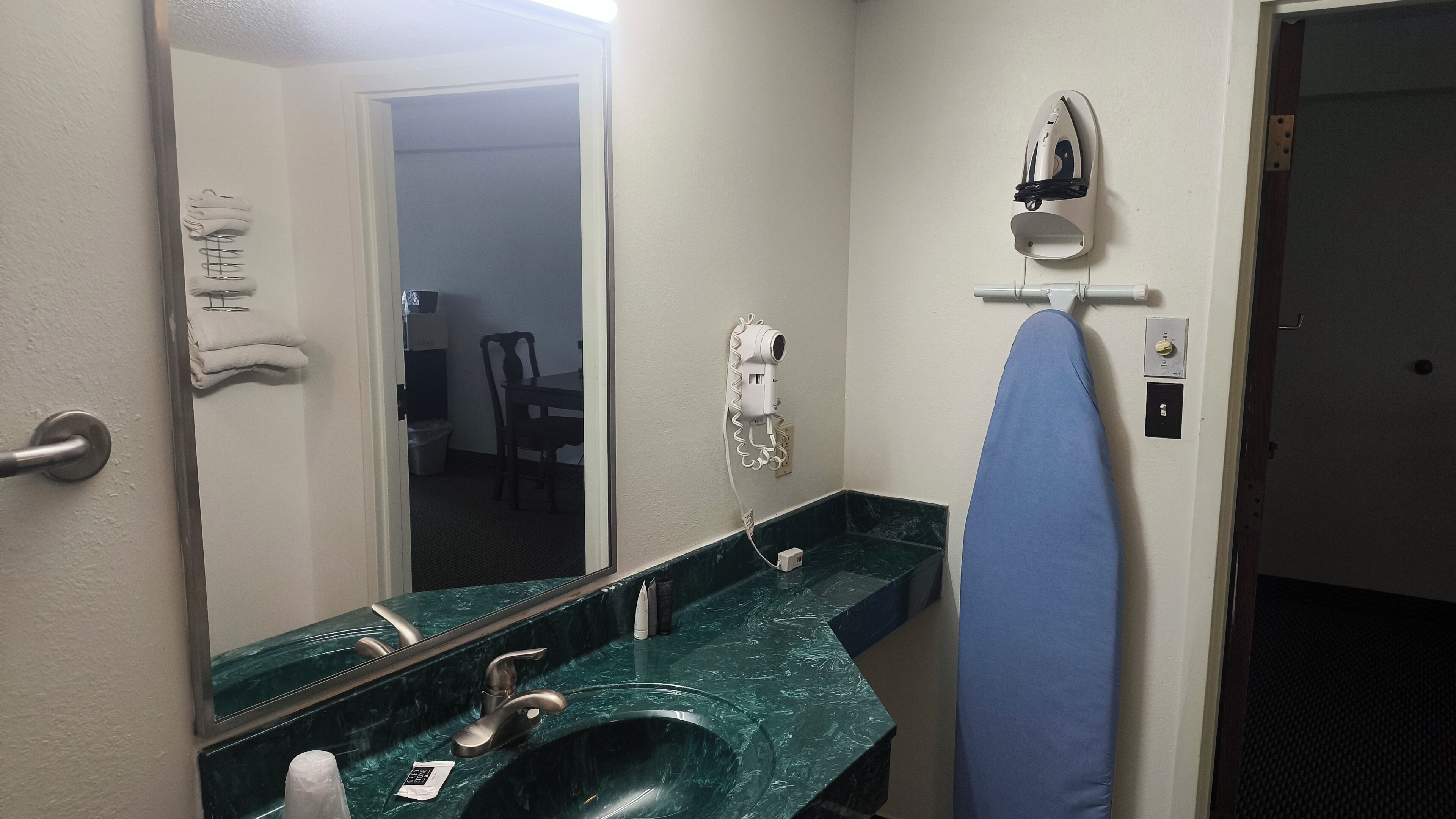 A bathroom with a sink, mirror, and an ironing board.