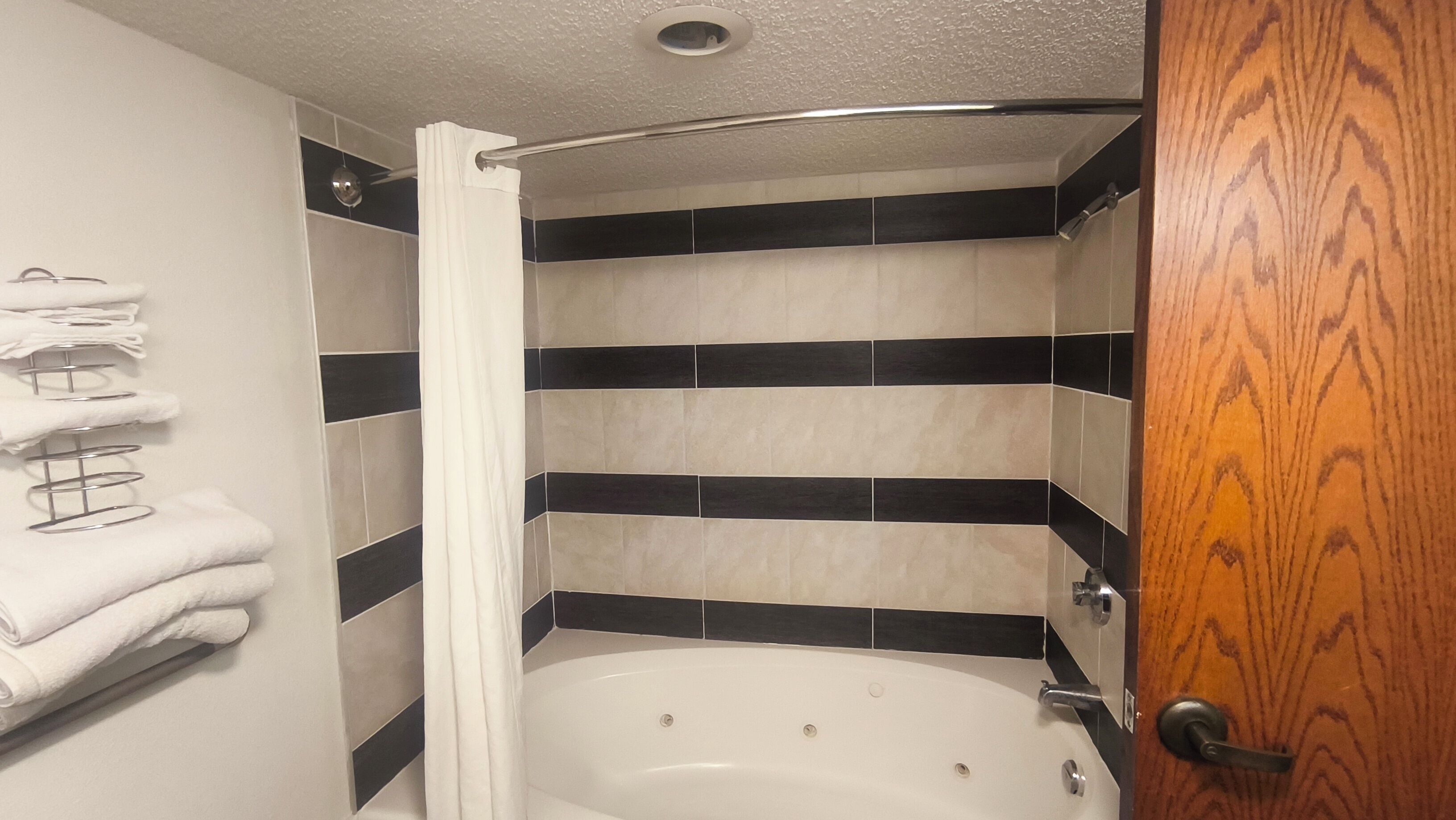 A bathroom with a bathtub, a shower curtain, and a towel rack with folded towels.