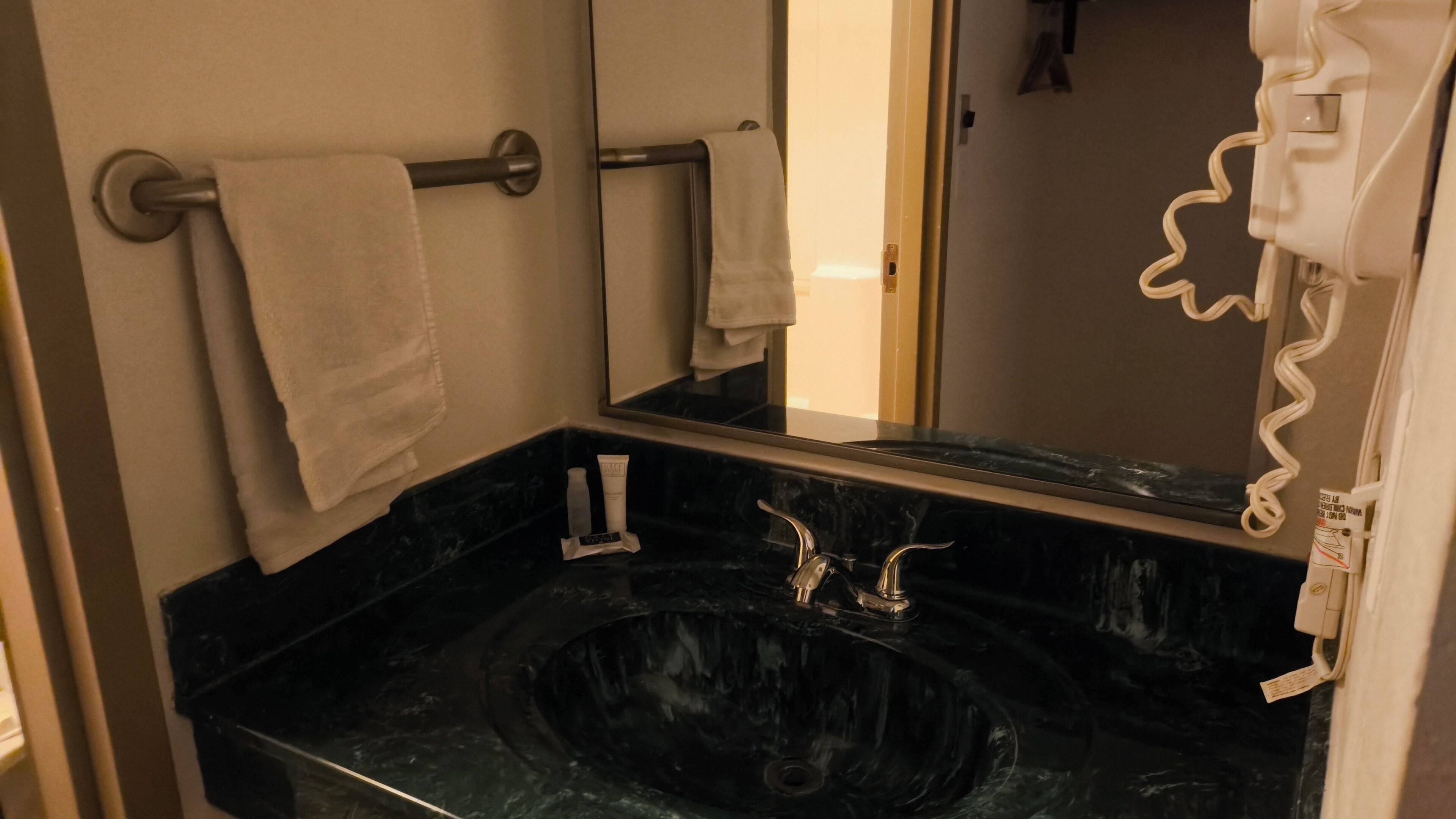A bathroom with a black marble sink, a mirror, and a towel rack.