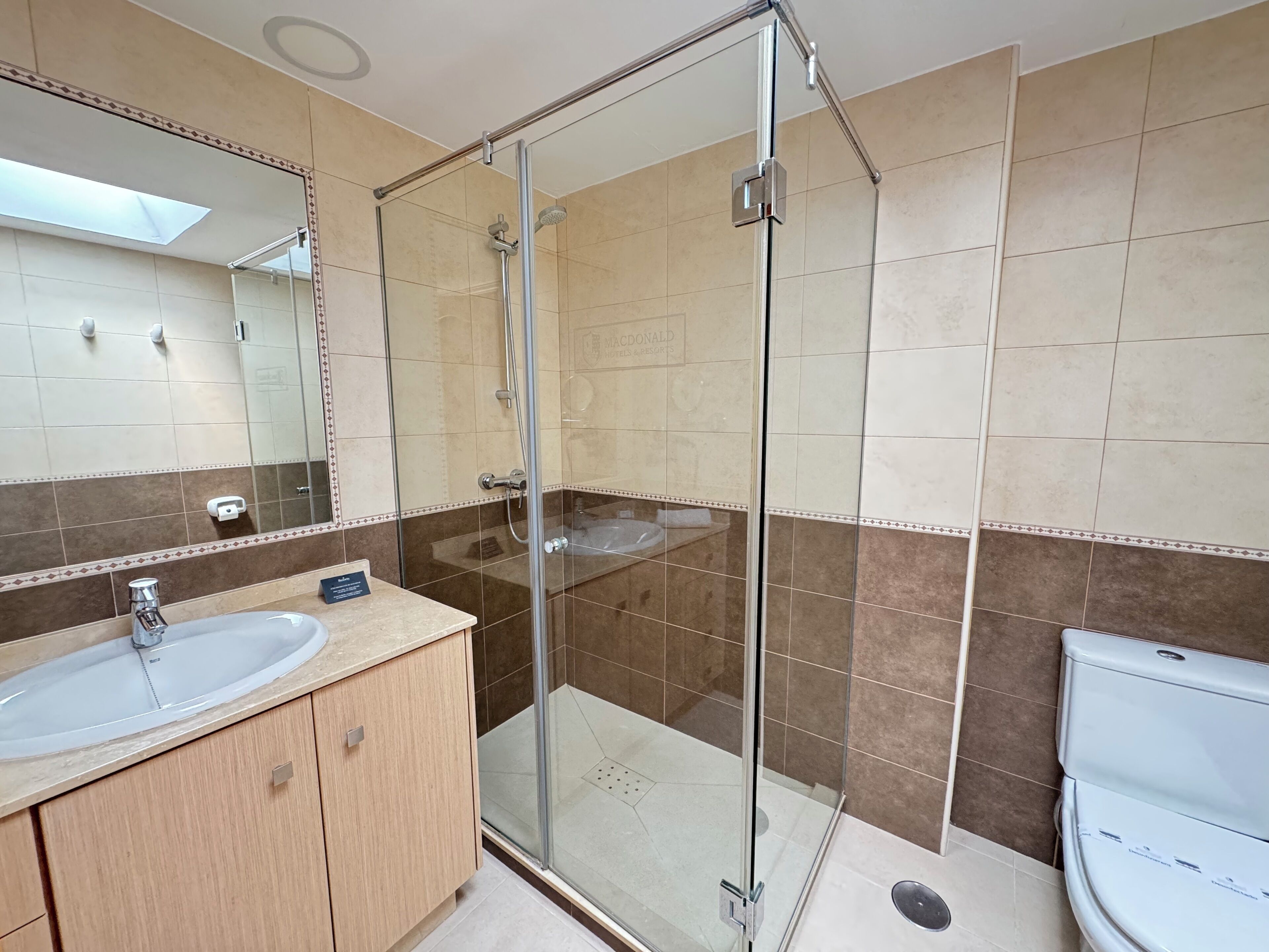 A modern bathroom with a glass-enclosed shower, a sink, and a toilet.