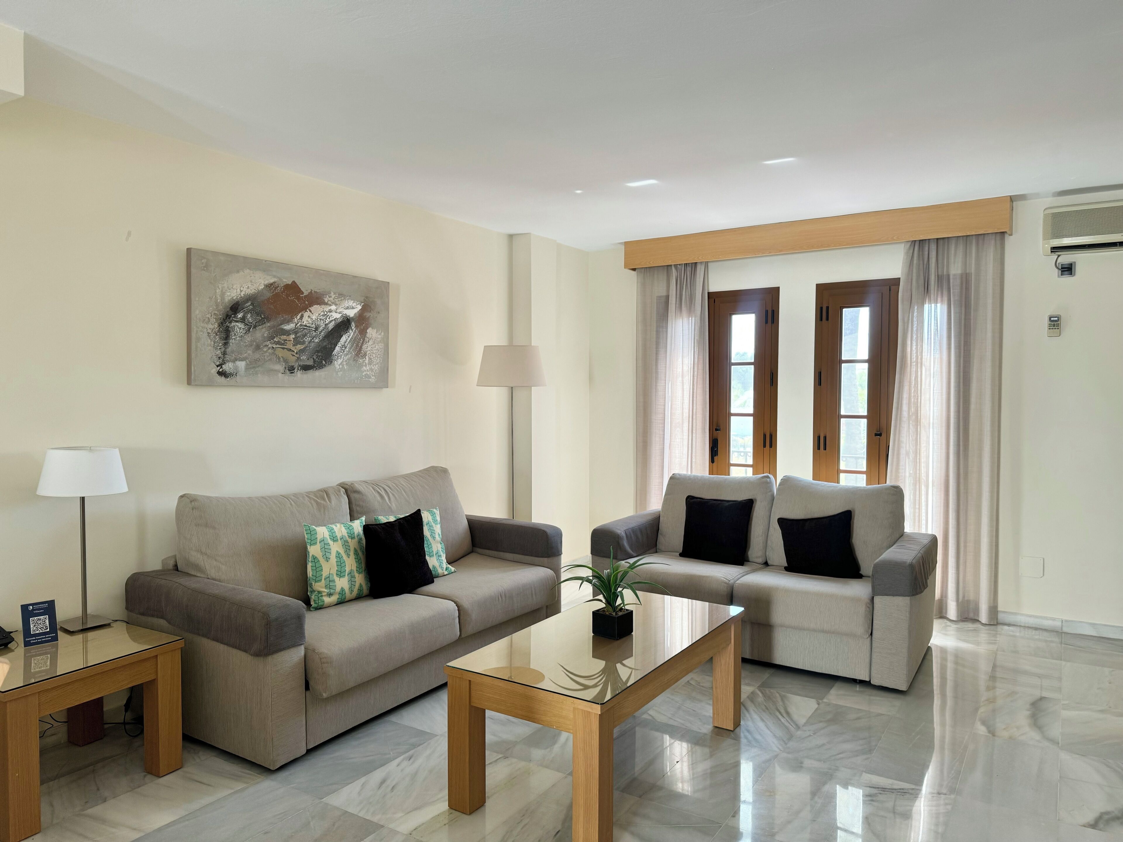 A modern living room with two sofas, a coffee table, a lamp, and a painting on the wall.