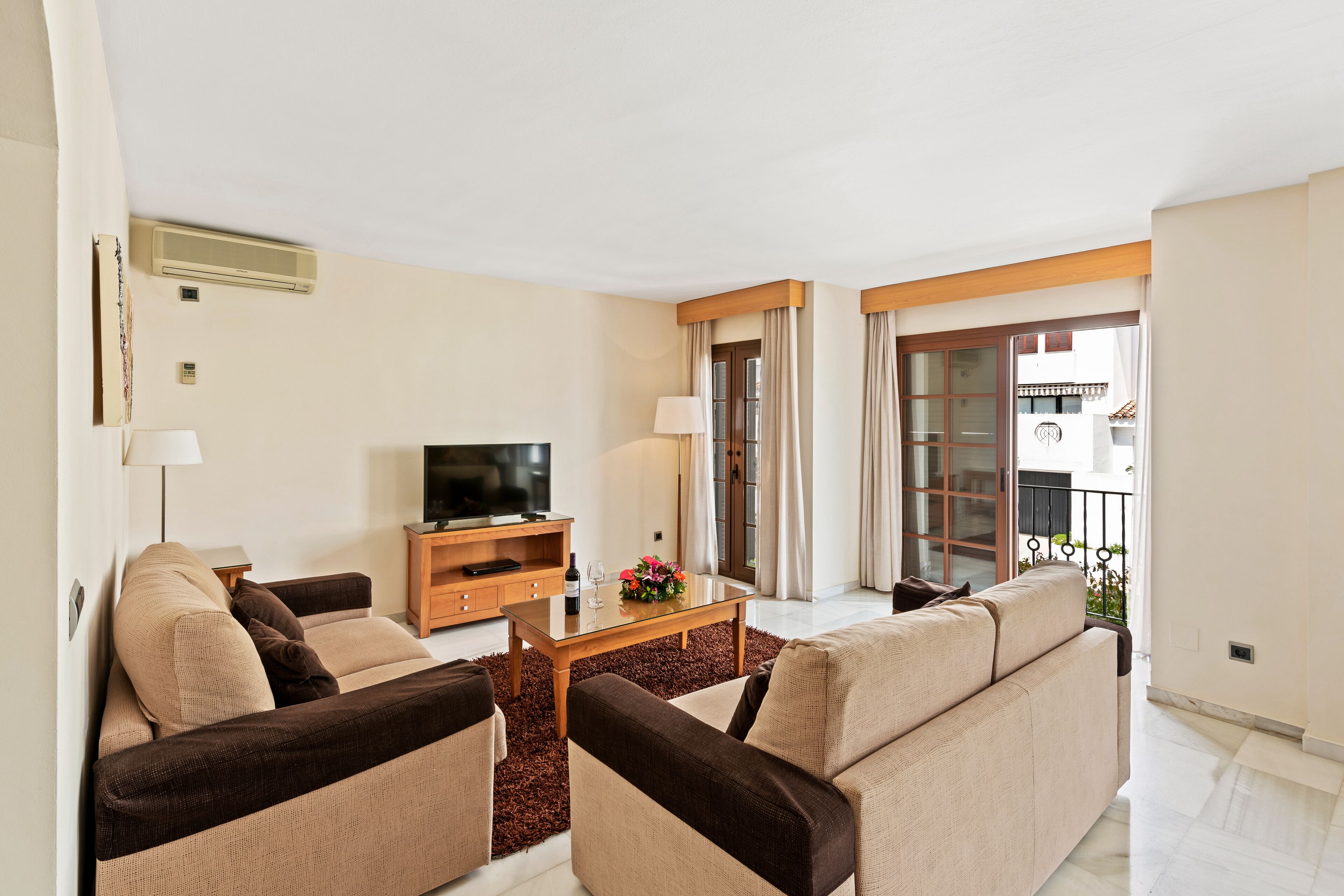Un salon moderne comprenant un ensemble de canapés, une table basse, un téléviseur à écran plat et un balcon avec vue.