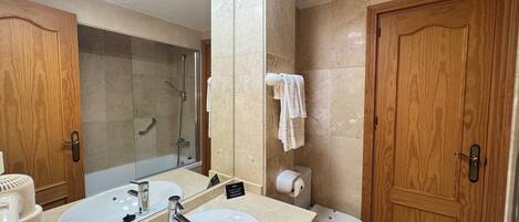 Een badkamer met een wastafel, spiegel, douche, toilet en houten deuren.