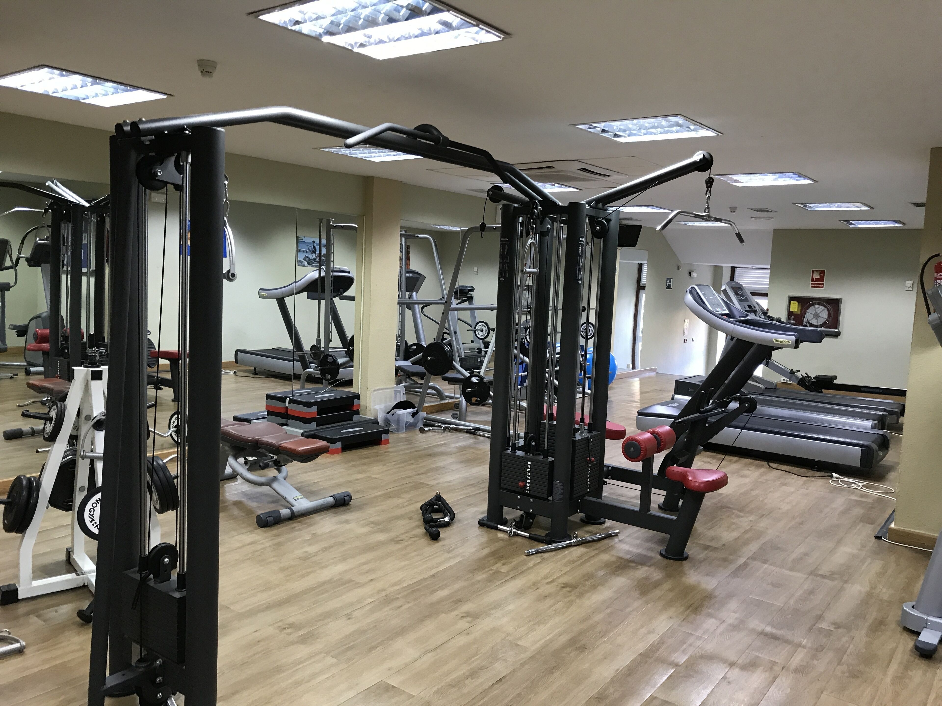 Een sportschool met diverse fitnessapparatuur, waaronder loopbanden en krachttoestellen.