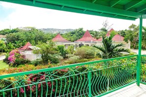 A balcony with a green railing overlooking a garden with red-roofed buildings and lush greenery. - Villa Sonate (Runaway Bay)