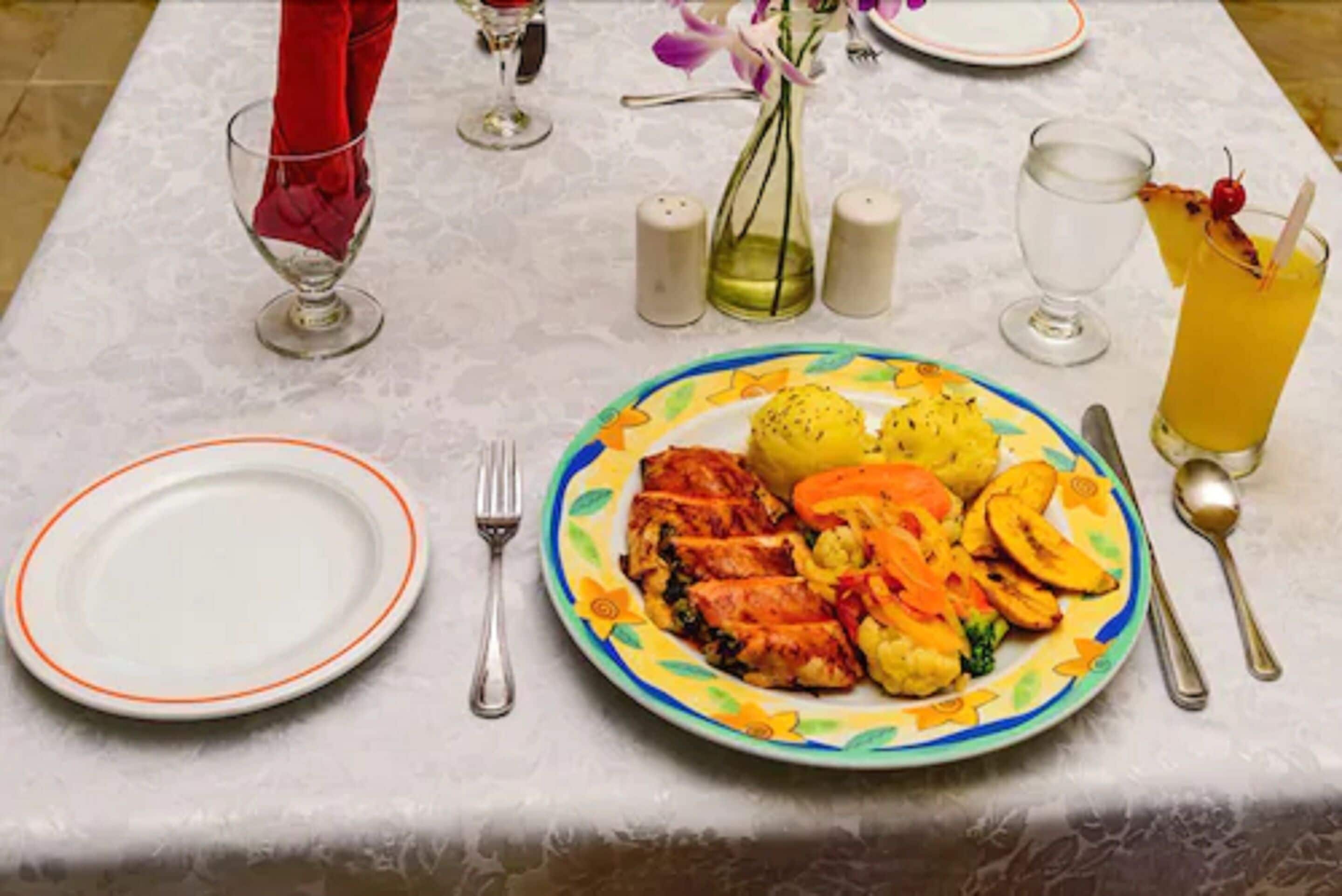 A table set for a meal with plates, cutlery, and a glass of orange juice.