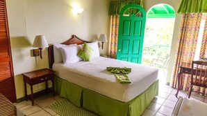 Une chambre à coucher avec un lit, deux tables de chevet, une lampe, une porte verte et une vue sur l’extérieur.