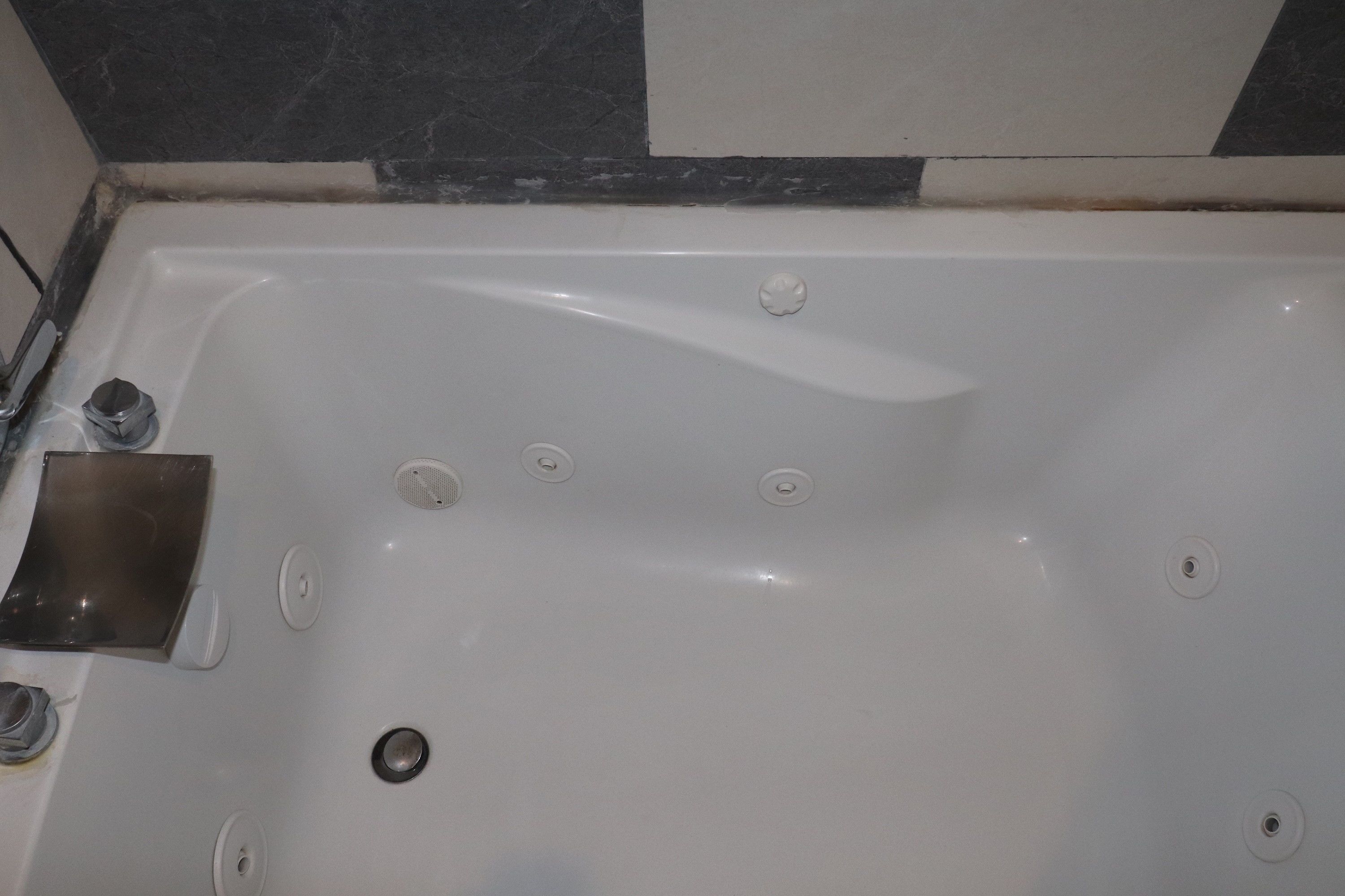 A white bathtub with multiple faucets and a drain.
