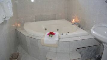 Un baño con una bañera grande, un lavabo y un cubo de basura.