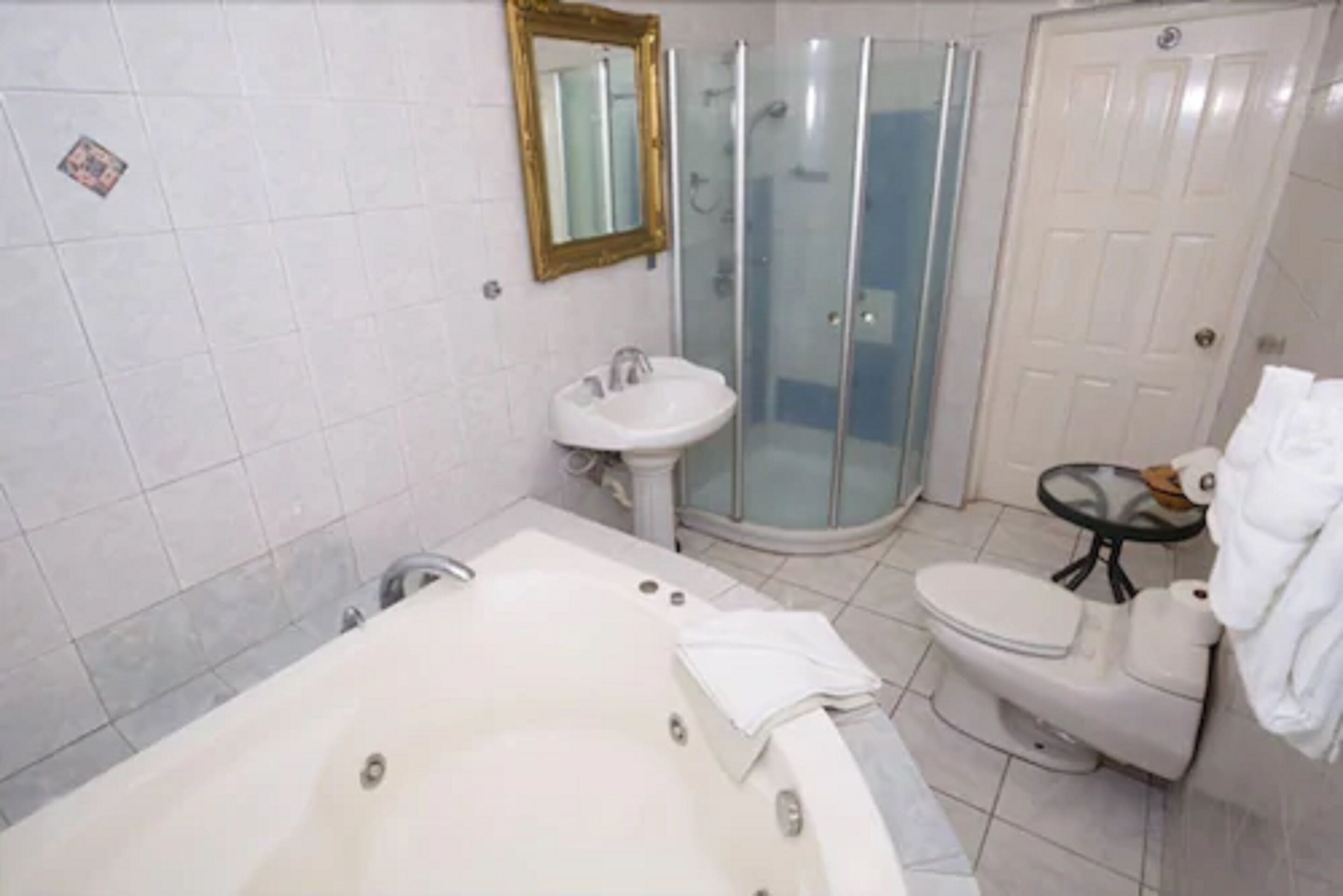 A bathroom with a bathtub, a sink, a toilet, and a glass shower enclosure.