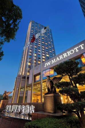 Ein JW Marriott Hotel mit auffälliger Beschilderung, einer Statue und einem Wasserspiel vor der Fassade.
