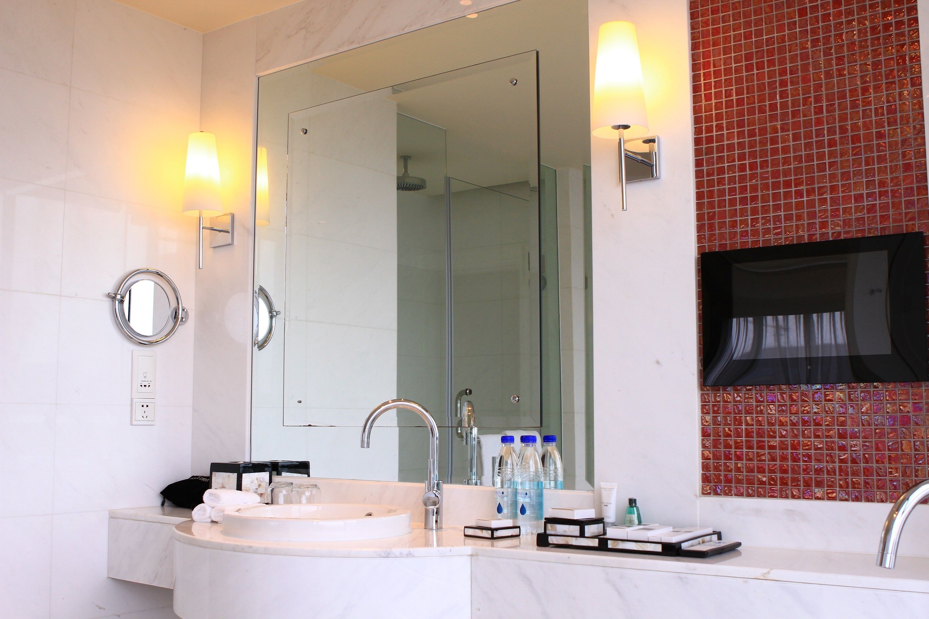 A modern bathroom with a large mirror, a round sink, and a glass shower enclosure.