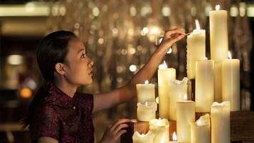 A person arranging candles in a dimly lit room with a patterned wall and a wooden counter.