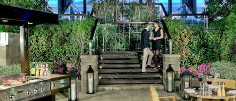 A restaurant with outdoor seating, a grill, and a staircase leading to a higher level.