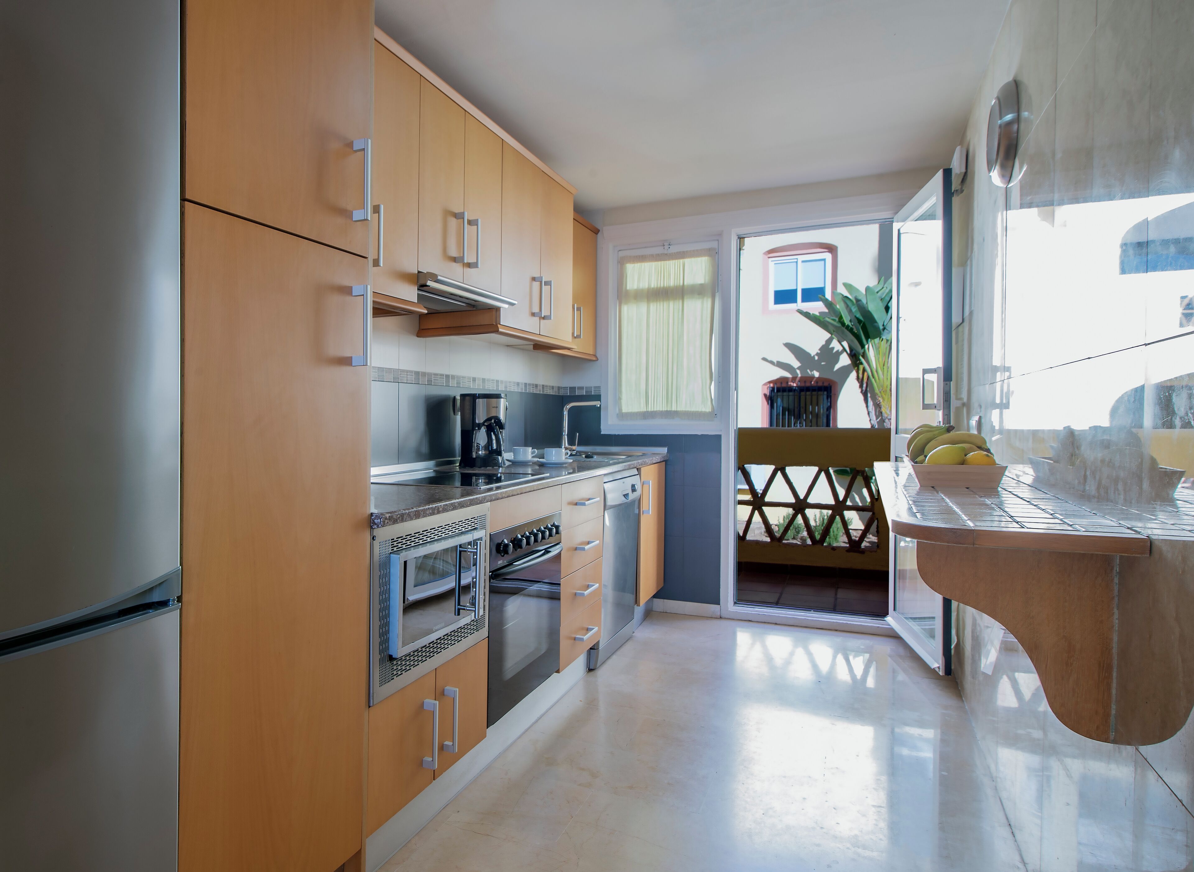 Eine moderne Küche mit Holzausstattung, Edelstahlgeräten und Blick auf den Balkon.