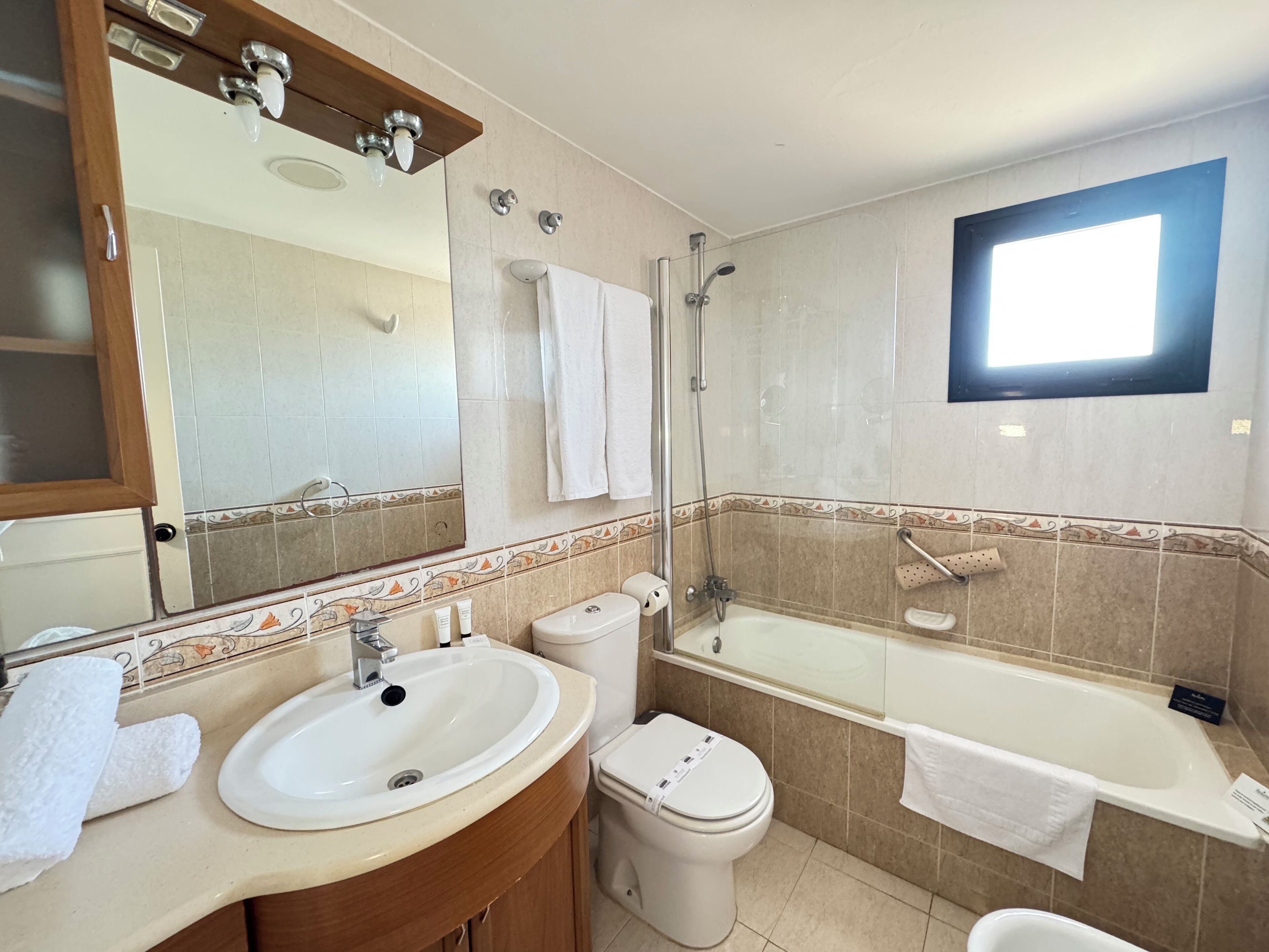 Et badeværelse med vask, toilet, badekar og bruser.