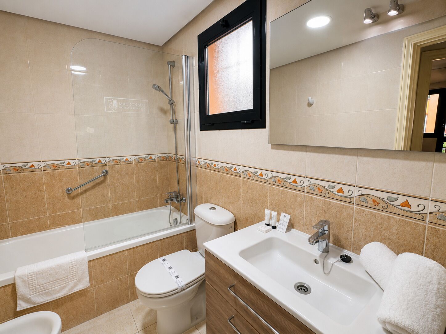 Ein Badezimmer mit Badewanne, Toilette, Waschbecken und Spiegel.