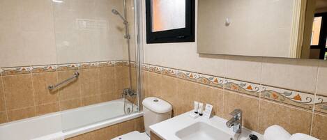 A bathroom with a bathtub, toilet, sink, and a mirror.