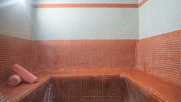 A tiled room with a bench and a rolled towel.