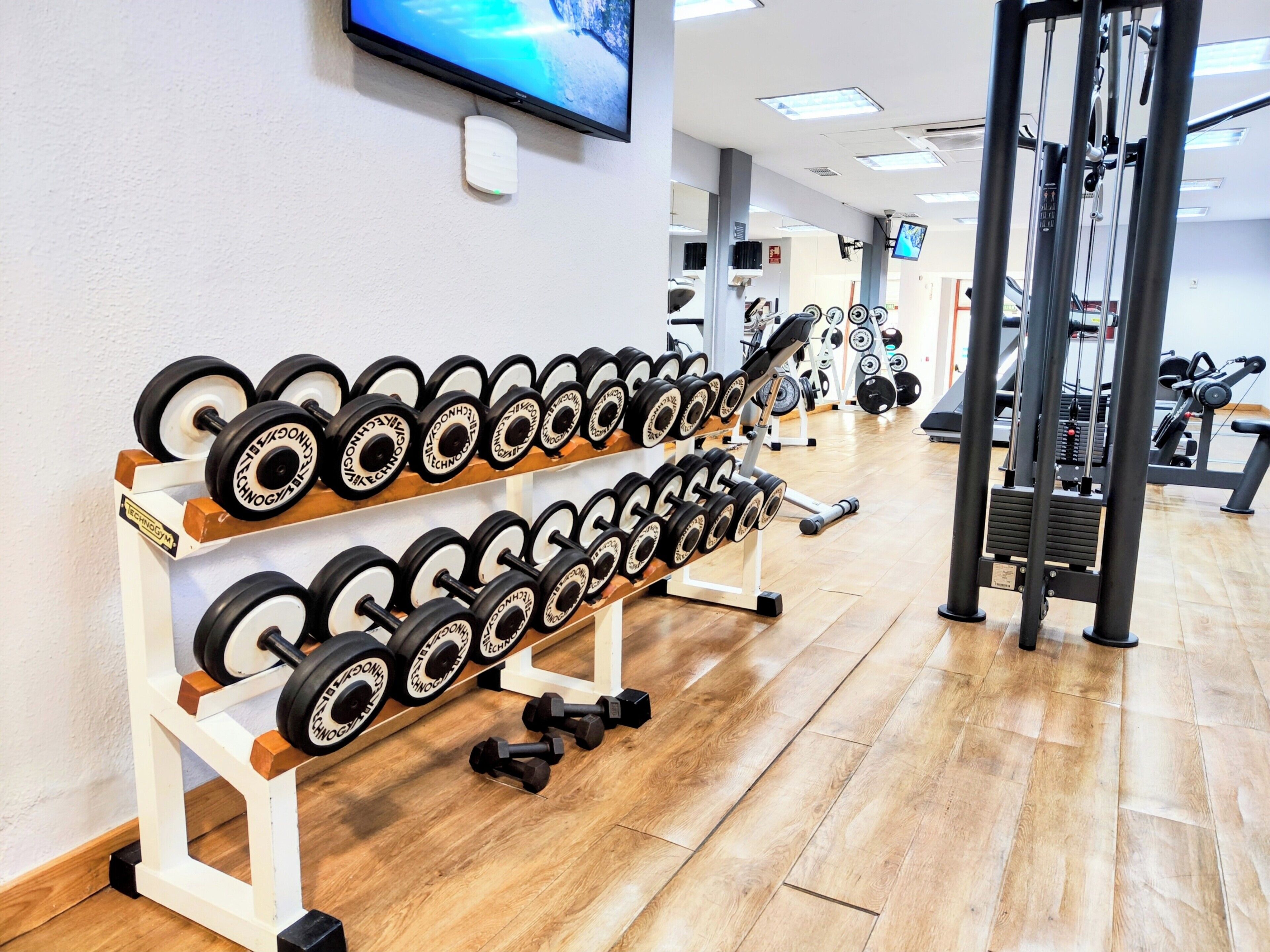 A gym with weightlifting equipment, including dumbbells and a squat rack.