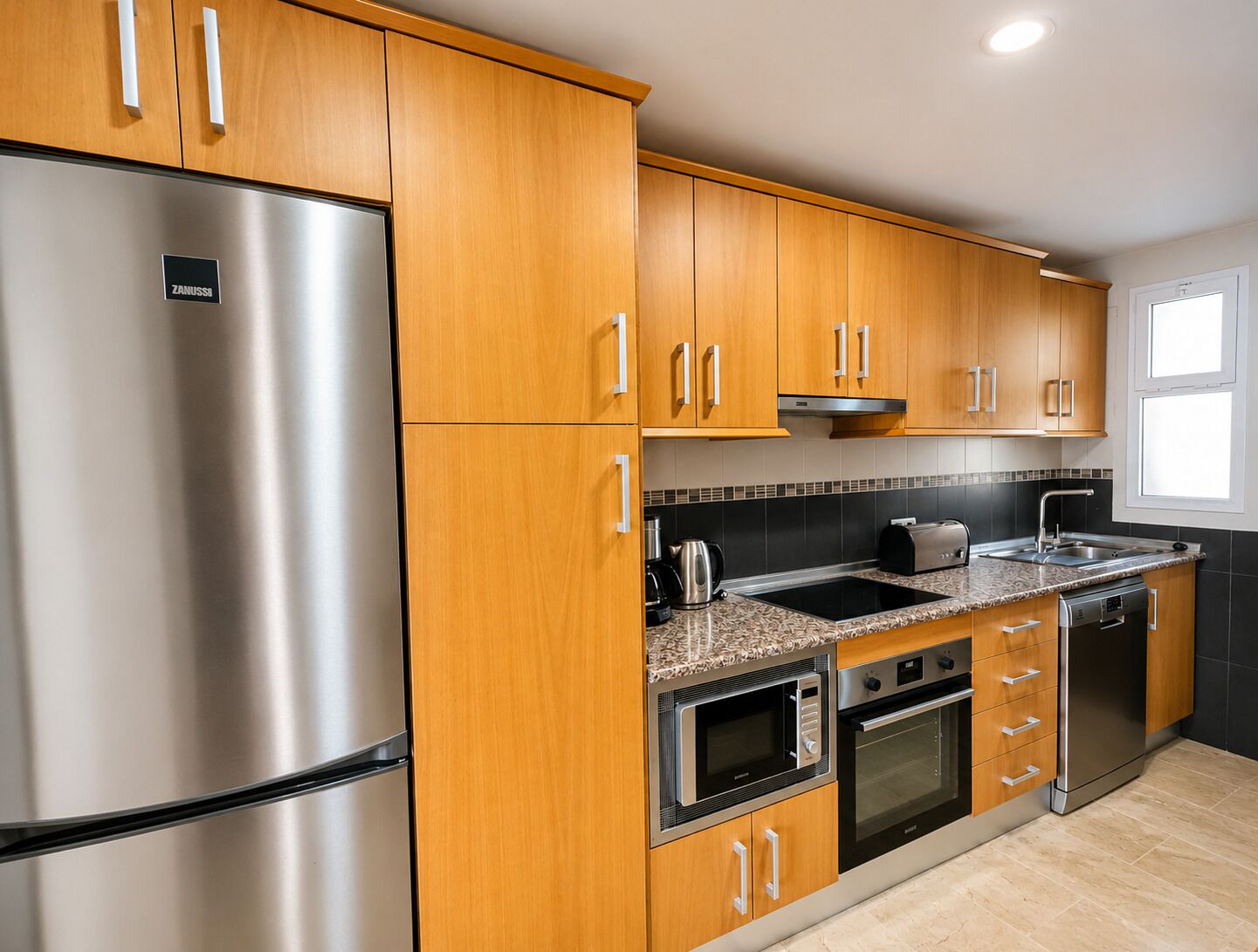 A modern kitchen with wooden cabinets, stainless steel appliances, a built-in oven, and a dishwasher.