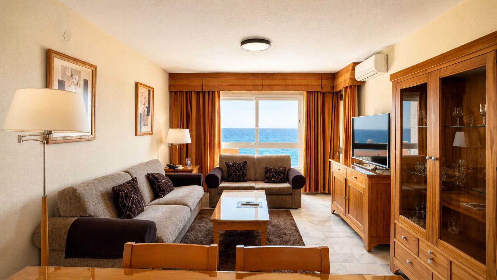 Une chambre d’hôtel comprenant un canapé, une table basse, un téléviseur et un meuble avec des portes en verre.
