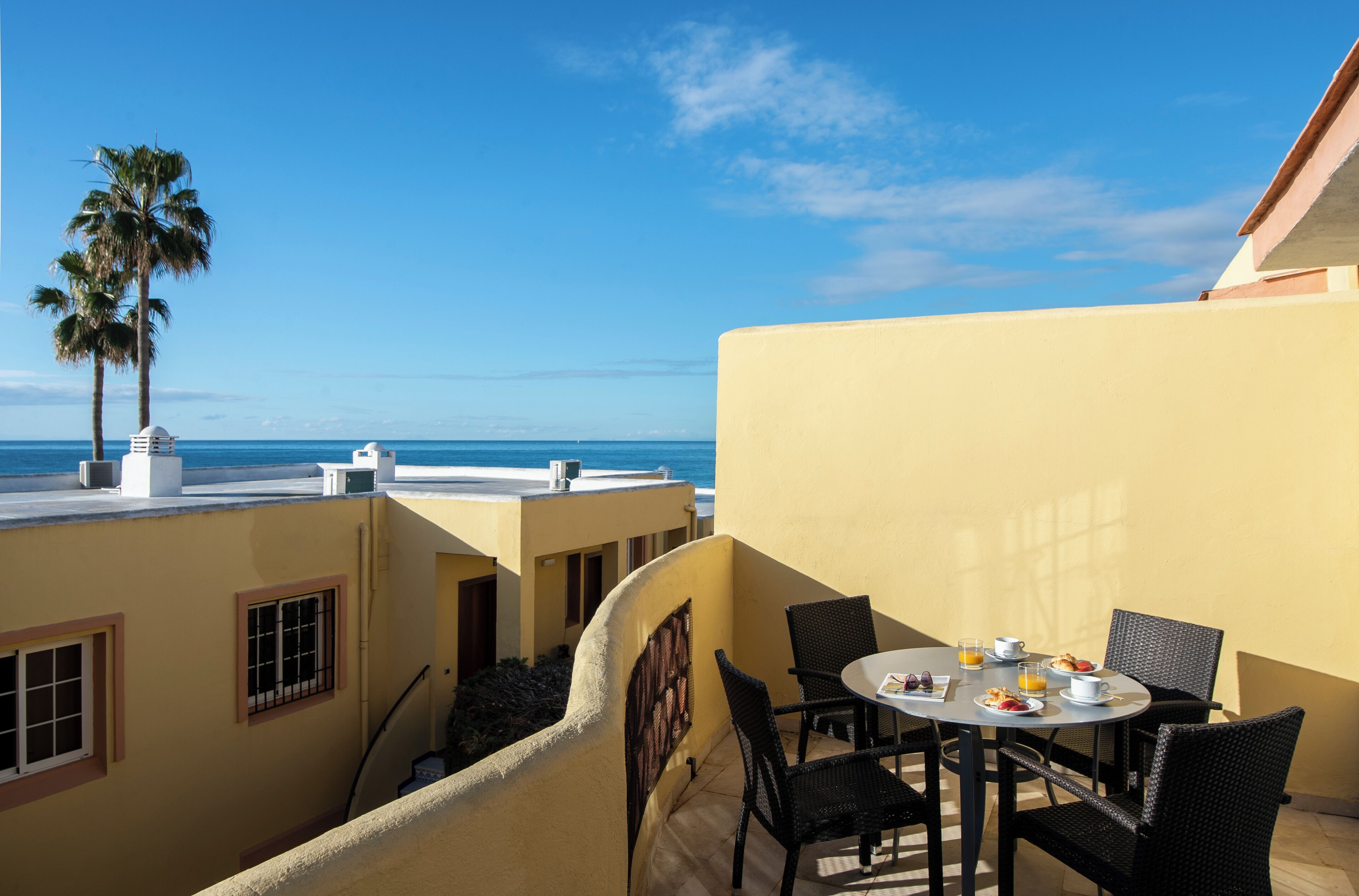 En balkon med et morgenbord, udsigt over havet.