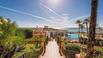 Un resort con piscina, palmeras y una vista despejada del mar.