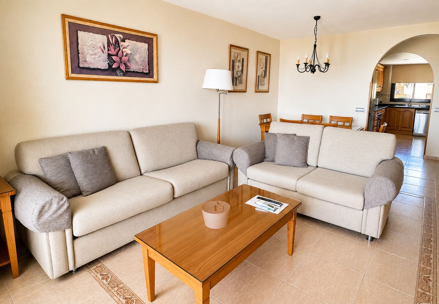 A living room with two sofas, a coffee table, a lamp, and a chandelier.