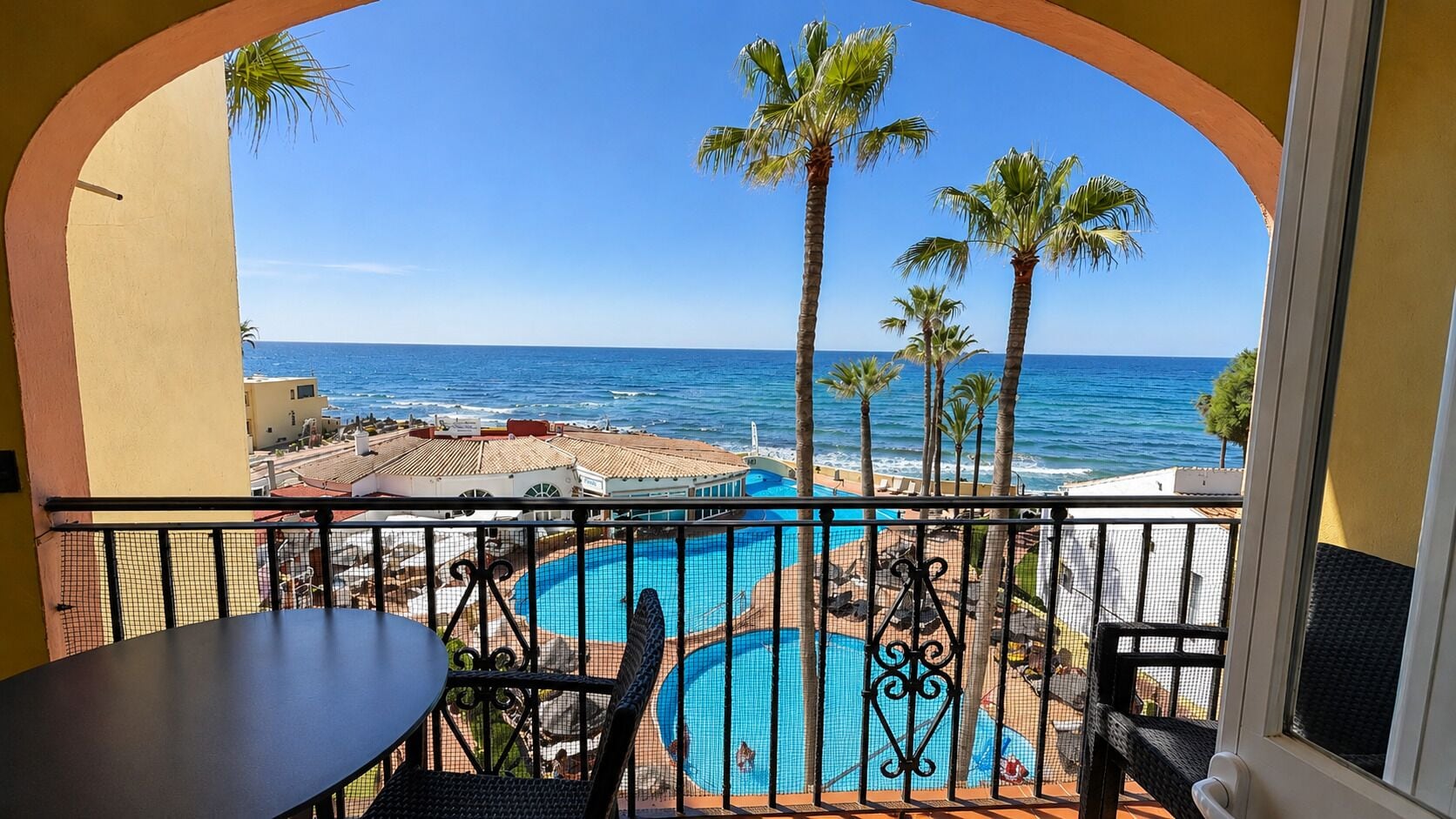 Un balcon avec vue sur une piscine et l’océan.
