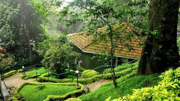 A traditional building with a tiled roof surrounded by lush greenery and terraced gardens.