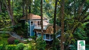 Una casa en el árbol con balcón, rodeada de un bosque frondoso.