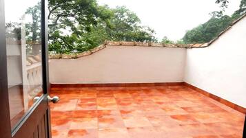 Terraço no telhado com telhas de terracota, uma parede branca e um parapeito de pedra.