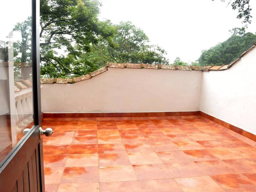 Terraço no telhado com telhas de terracota, uma parede branca e um parapeito de pedra.