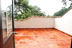 Una terraza en la azotea con baldosas de terracota, un muro blanco y una barandilla de piedra.