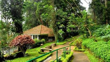A small building with a tiled roof, surrounded by lush greenery and a paved pathway.
