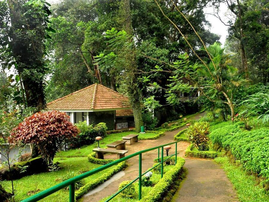 A small building with a tiled roof, surrounded by lush greenery and a paved pathway.