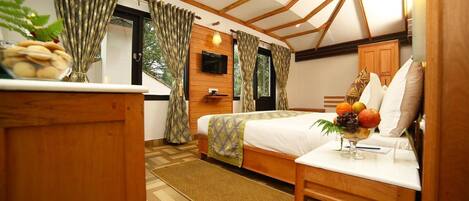 A bedroom with a bed, wooden furniture, a TV, and a window with curtains.
